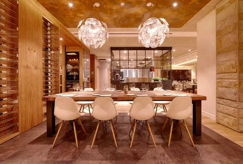 Innenansicht des Restaurants RIVA in Deidesheim mit moderner Holzwandtäfelung, die als Weinregal dient und einladend gedecktem Tisch.