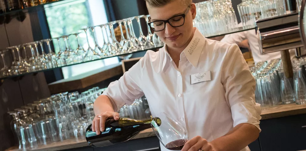 junge Frau schenkt Wein aus vor Theke im Parkhotel Schillerhain
