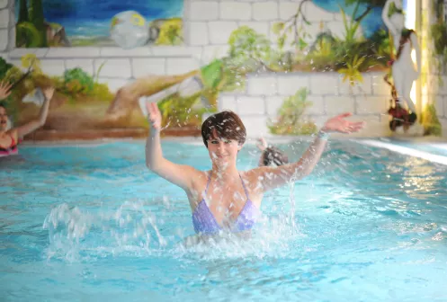 Frau im Badeanzug spritzt mit Wasser in Swimmingpool
